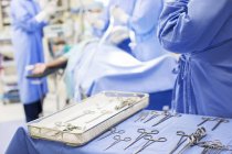 Krankenschwester steht mit Operationswerkzeug am Tablett im Operationssaal — Stockfoto
