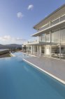 Tranquille maison de luxe moderne vitrine piscine à débordement extérieure — Photo de stock