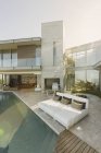 Sunny lusso casa vetrina patio esterno con sedie a sdraio a bordo piscina — Foto stock