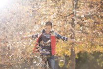 Ragazzo giocoso che gioca in foglie di autunno — Foto stock