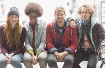 Happy young friends smiling on urban bench — Stock Photo
