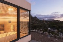Illuminato casa vetrina bagno tra paesaggio scosceso al tramonto — Foto stock