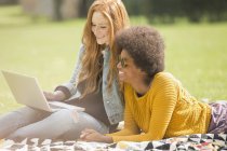 Женщины используют ноутбук вместе в парке — стоковое фото