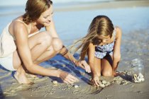 Mãe e filha brincando na areia — Fotografia de Stock