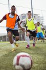 Soccer players running to kick ball on field — Stock Photo
