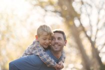 Liebevoller Vater und Sohn huckepack im Park — Stockfoto