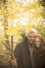 Portrait smiling couple with walking stick in autumn woods — Stock Photo