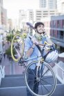 Homme portant un vélo sur les marches de la ville — Photo de stock