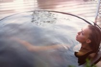 Serene teenage girl soaking in hot tub on patio — Stock Photo