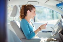 Woman texting with cell phone inside car — Stock Photo
