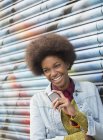 Жінка з мобільним телефоном посміхається проти стіни графіті — стокове фото