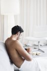 Hombre en toalla usando tableta digital en el dormitorio en casa - foto de stock