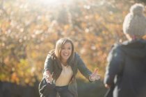 Enthusiastic mother reaching for son in autumn park — Stock Photo
