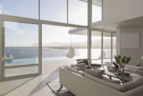 Sunny, tranquille maison de luxe moderne vitrine salon intérieur avec vue sur l'océan — Photo de stock