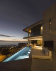 Illuminated home showcase exterior patio with lap pool and ocean view — Stock Photo