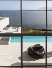 Moderna casa de luxo vitrine exterior piscina infinita com vista para o mar ensolarada — Fotografia de Stock