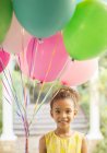 Chica joven sosteniendo montón de globos - foto de stock