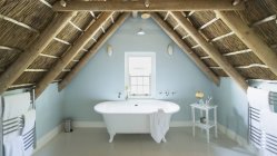 Luxo sótão casa de banho sob telhado de madeira — Fotografia de Stock