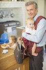 Бизнесмен, несущий ребенка на кухне — стоковое фото