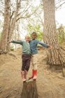 Bambini che si arrampicano sul ceppo nella foresta — Foto stock