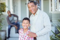 Porträt eines lächelnden Großvaters und Enkels vor dem Haus — Stockfoto