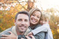 Портрет усміхненої сім'ї, що обіймається перед осіннім листям — стокове фото