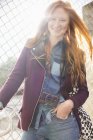 Glückliche junge Frau lächelt am Maschendrahtzaun — Stockfoto