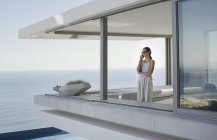Frau telefoniert auf moderner, luxuriöser Wohnvitrine Außenterrasse mit Meerblick — Stockfoto