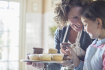 Großmutter bietet Enkelin Cupcakes an — Stockfoto