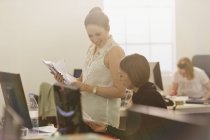 Бізнес-леді обговорюють документи за комп'ютером в офісі — стокове фото