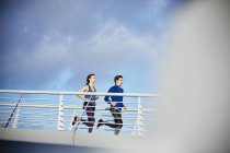 Пара бегущих по солнечному пешеходному мосту — стоковое фото