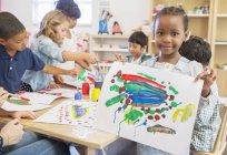 Student showing off finger painting in classroom — Stock Photo