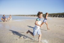 Children running in waves on beach — Stock Photo