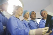 Surgeons looking at x-ray during surgery in operating theater — Stock Photo