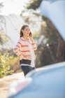 Женщина разговаривает по мобильному телефону с автомобильным капюшоном поднятым на обочине дороги — стоковое фото