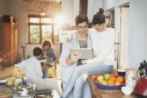 Усміхнена молода пара використовує цифровий планшет на кухні — стокове фото