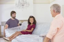 Family carrying couch with young girl sitting on top — Stock Photo