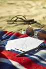 Листівки, сонцезахисні окуляри та сандалі на пляжі — стокове фото