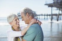 Seniorpaar umarmt sich am Strand — Stockfoto