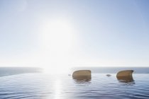 Sillas de césped en la piscina infinita con vistas al océano - foto de stock