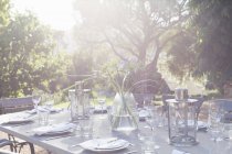 Place settings on sunny patio table — Stock Photo