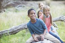Children sitting on log in forest — Stock Photo