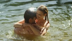 Liebespaar umarmt und schwimmt im sonnigen See — Stockfoto