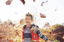 Портрет захопленого хлопчика, що кидає осіннє листя — стокове фото