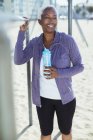 Donna in abbigliamento sportivo appoggiata al bar al parco giochi sulla spiaggia — Foto stock
