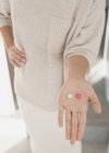 Жінка тримає, показуючи дві таблетки, рожевий і зелений — стокове фото
