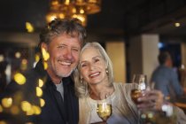 Porträt lächelndes Seniorenpaar prostet Weißweingläser in Bar zu — Stockfoto