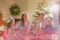 Family wearing paper crowns at Christmas dinner table — Stock Photo