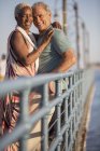 Porträt eines lächelnden Senioren-Paares, das sich auf der Seebrücke umarmt — Stockfoto