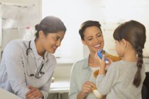 Female pediatrician and mother watching girl patient using inhaler in examination room — Stock Photo